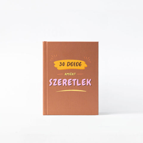 Barna keményfedeles könyv, rajta színes felirattal: 30 dolog, amiért szeretlek, fehér háttér előtt
