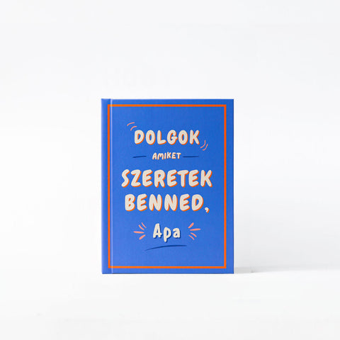 Kék borítójú ajándékkönyv, rajta a felirat: Dolgok, amiket szeretek benned, Apa fehér háttér előtt