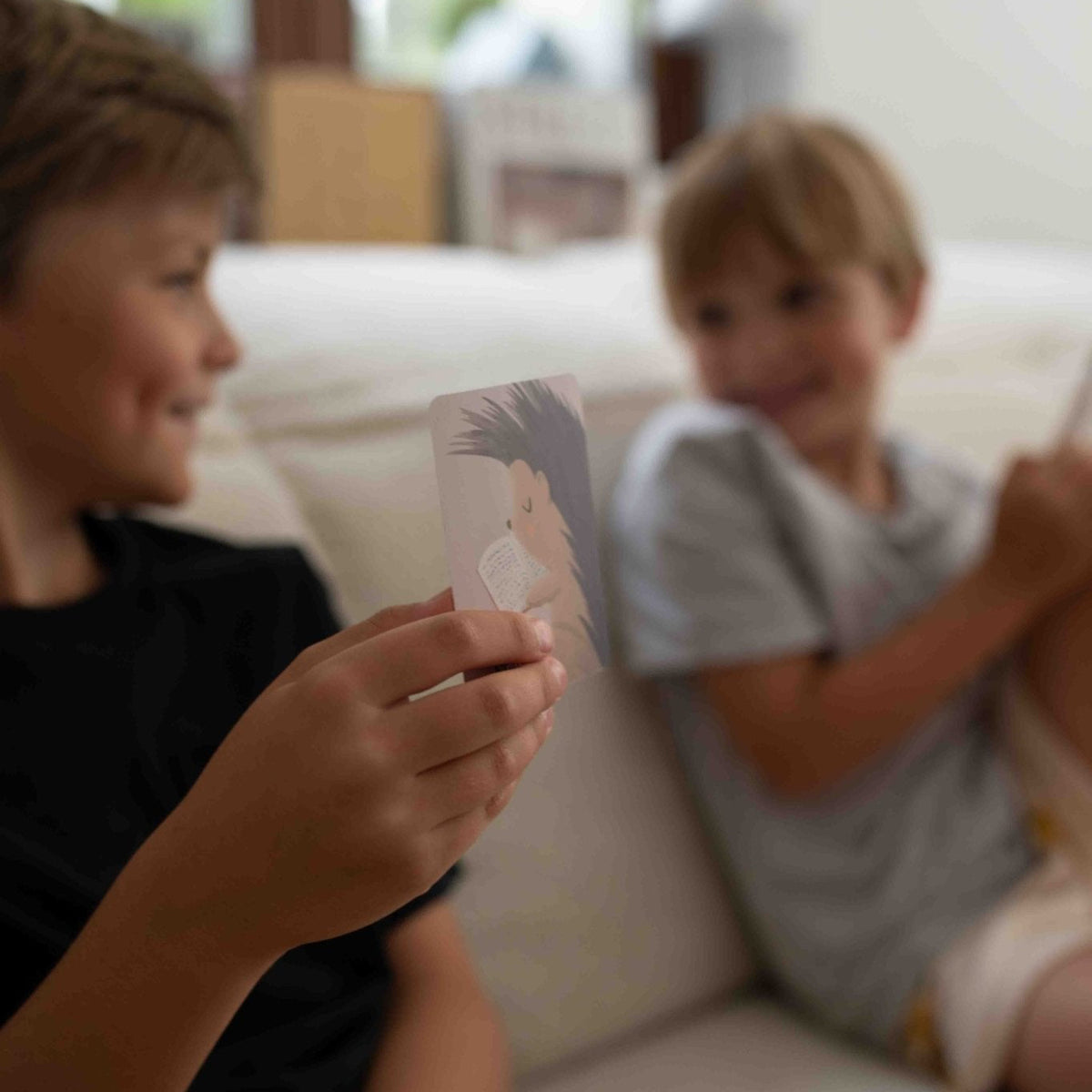 Two boys talking about a card on the sofa